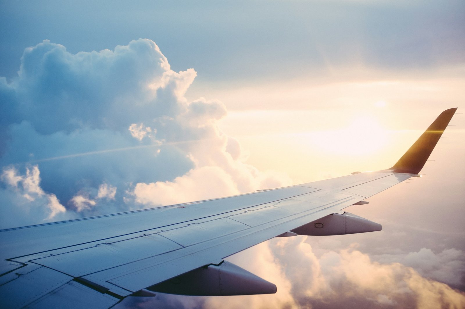 Aircraft wing above sunlit clouds at sunset